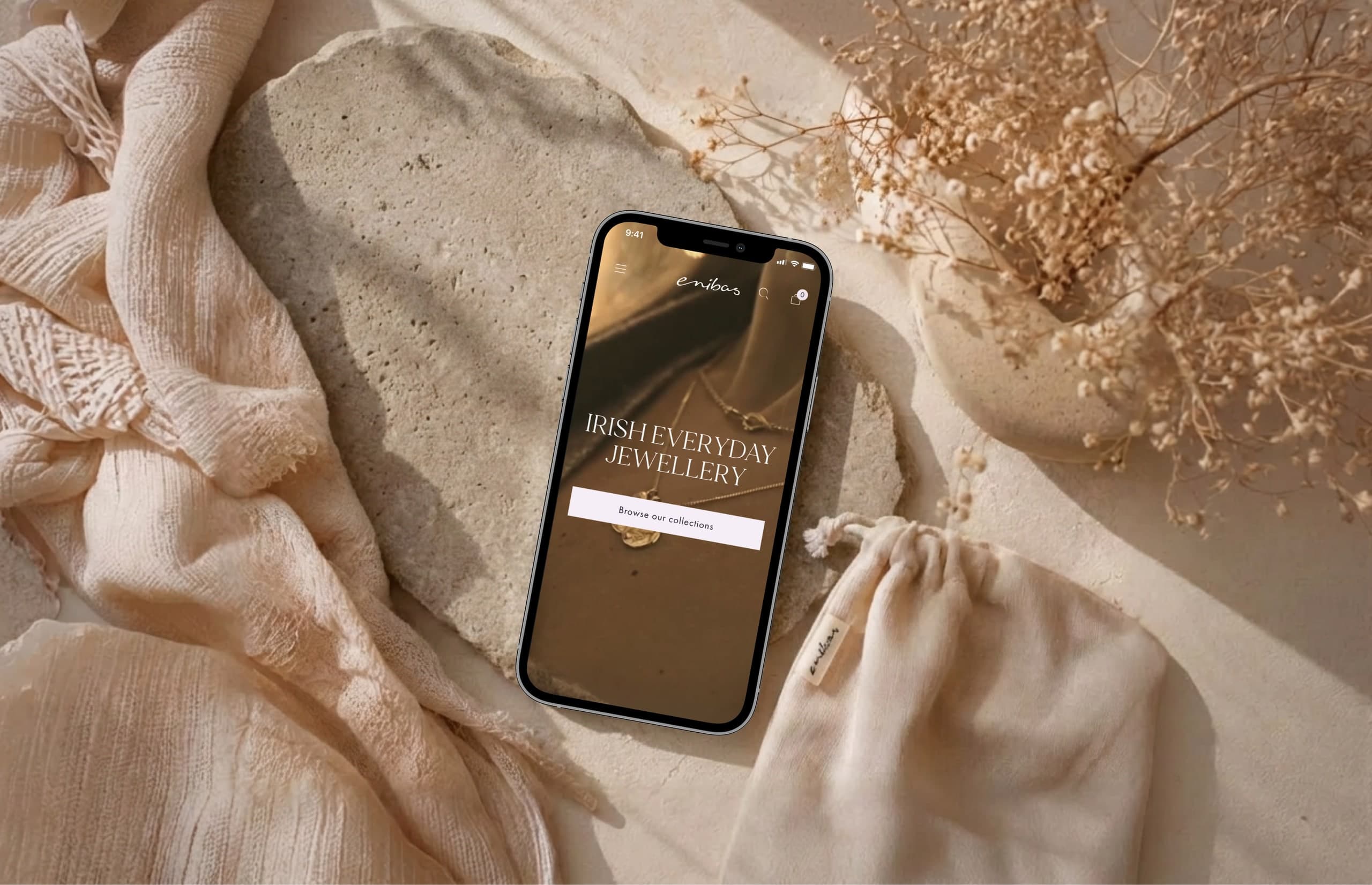 The Enibas jewellery store on a phone surrounded by soft fabrics and dried flowers