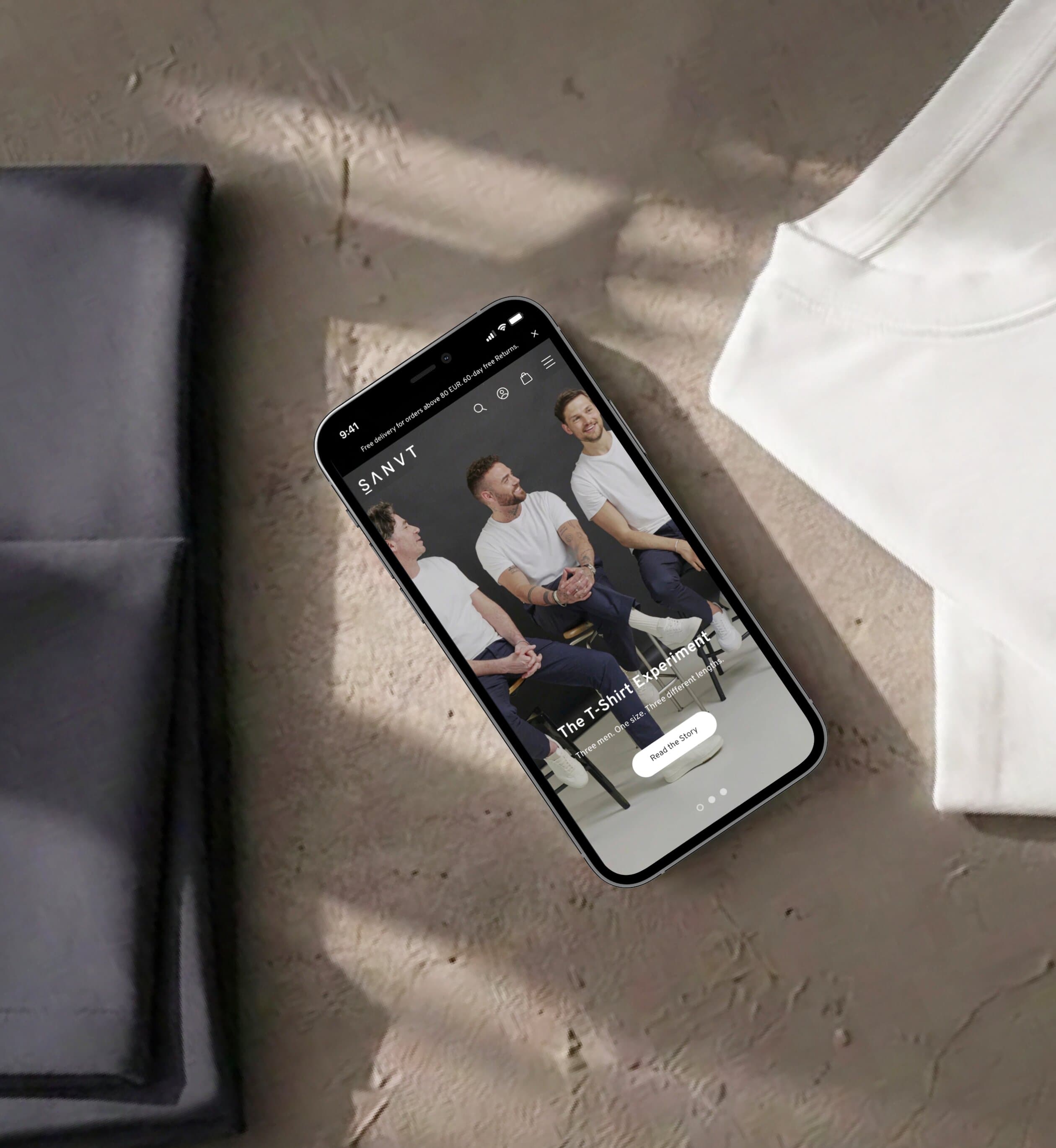Mobiler SANVT Store auf einem Smartphone, das zwischen gefalteten Premium-Kleidungsstücken liegt